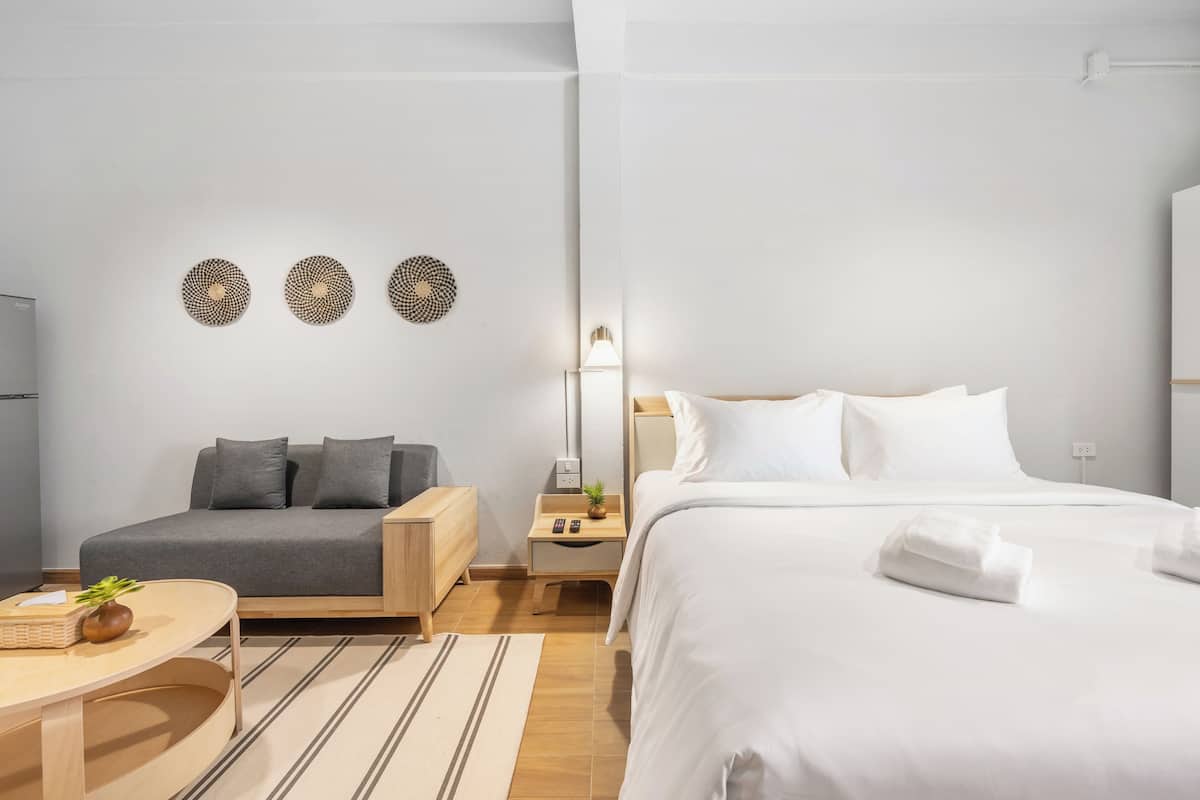 A modern hotel room with a bed, a sofa, a small table, and decorative wall art.