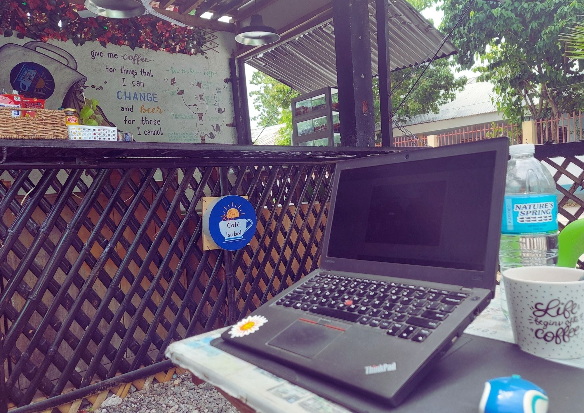 Una laptop sobre una mesa con una taza de café y un cartel sobre la preparación de café.