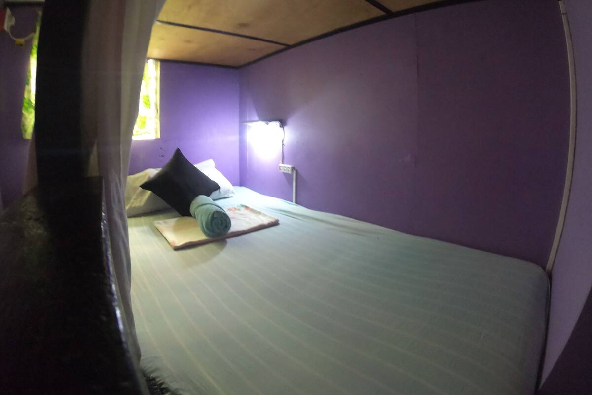 A compact room with a bed, a nightstand, and a window.