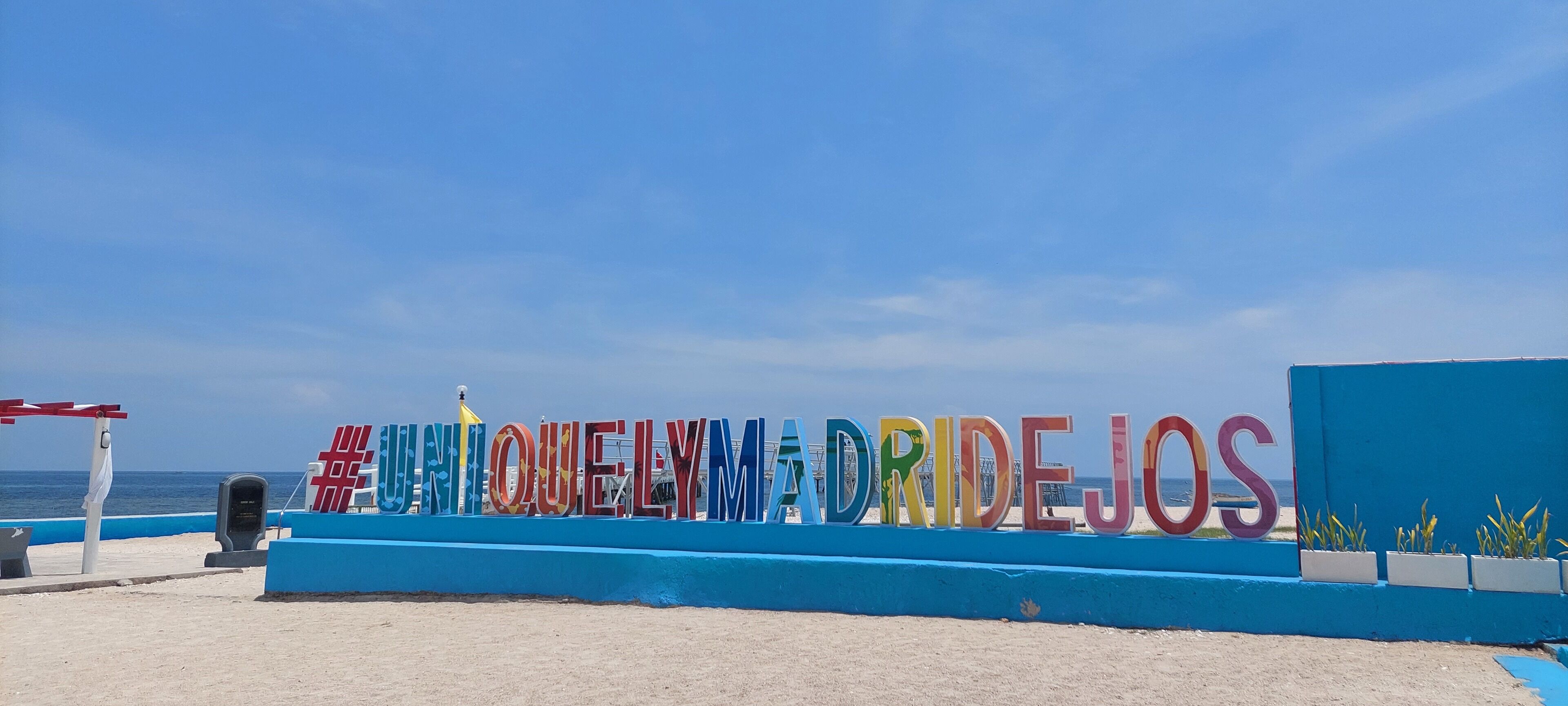 Ein Schild am Strand mit bunten Buchstaben, die einen Ortsnamen zeigen.