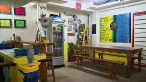 Habitació acollidora amb nevera, una taula amb una banca i diverses decoracions, incloent-hi una pissarra amb una llista.