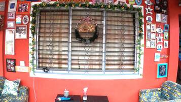 A room with a red wall, a window with metal bars, and two patterned sofas.
