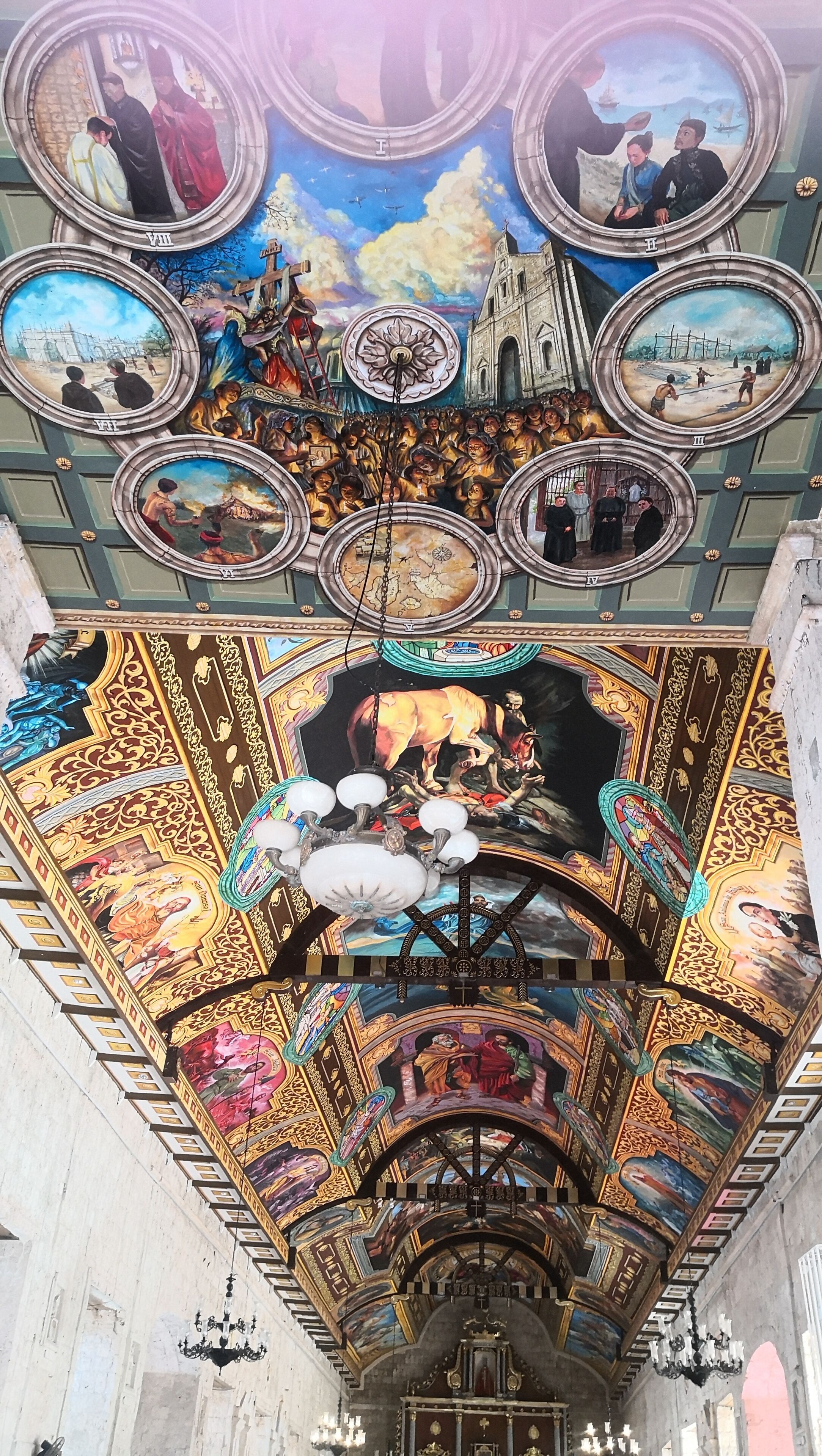 Un techo con frescos intrincados y una lámpara central.