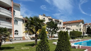 Un edificio residenziale con piscina, circondato da prati curati e alberi da giardino.