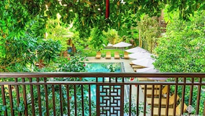 Ein üppiger Garten mit Pool, Liegestühlen und Sonnenschirmen.