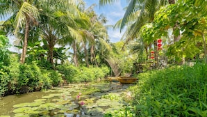 Ein friedlicher Garten mit Teich, üppigem Grün und einem kleinen Boot.