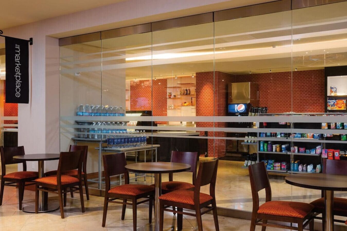 Una cafetería moderna con divisiones de vidrio, mesas y sillas de madera.