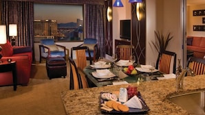 Une chambre d’hôtel avec un coin repas, un canapé et une vue sur le paysage urbain.