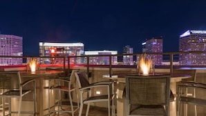 Un bar situé sur un toit, avec des places assises en plein air et une vue sur les toits de la ville illuminée la nuit.