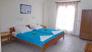 Una cama doble con una colcha azul, un armario de madera y un cuadro en la pared.