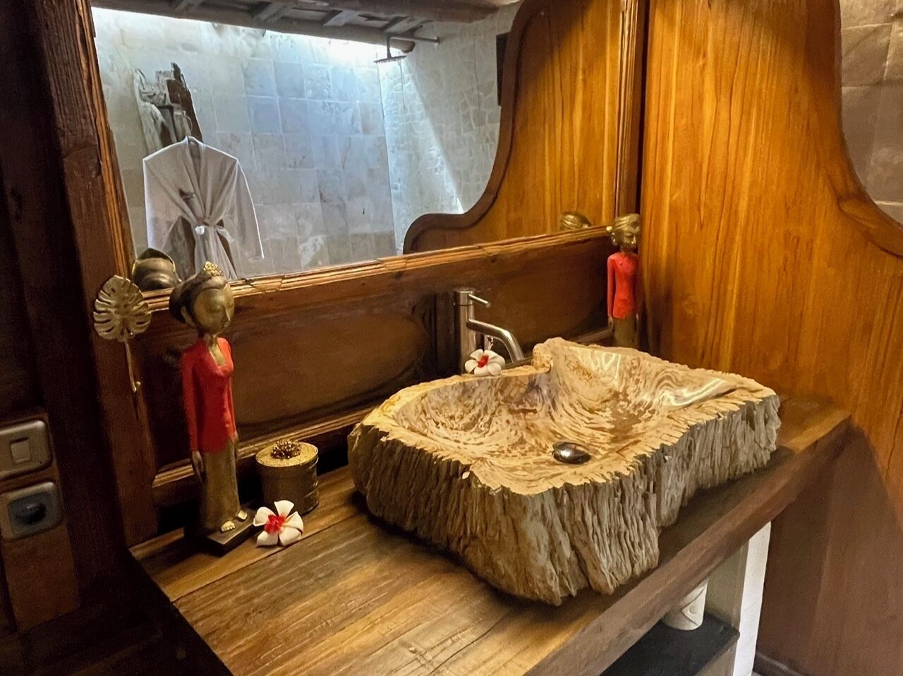 Une coiffeuse en bois dotée d’un lavabo original, réalisé à partir d’une souche d’arbre, d’un miroir et d’une petite statue.