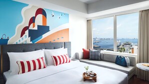 Ein modernes Hotelzimmer mit einem großen Bett, Blick auf die Stadt und einem Stadtbild-Wandgemälde.