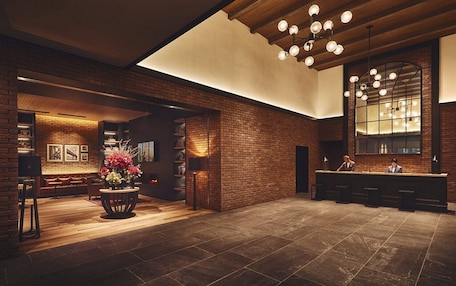 A spacious lobby with a brick wall, a reception desk, and a large mirror.