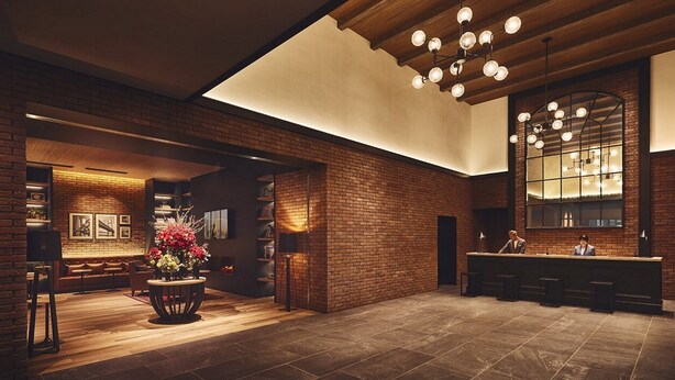 Eine geräumige Lobby mit Backsteinwand, einer Rezeption und einem großen Spiegel.