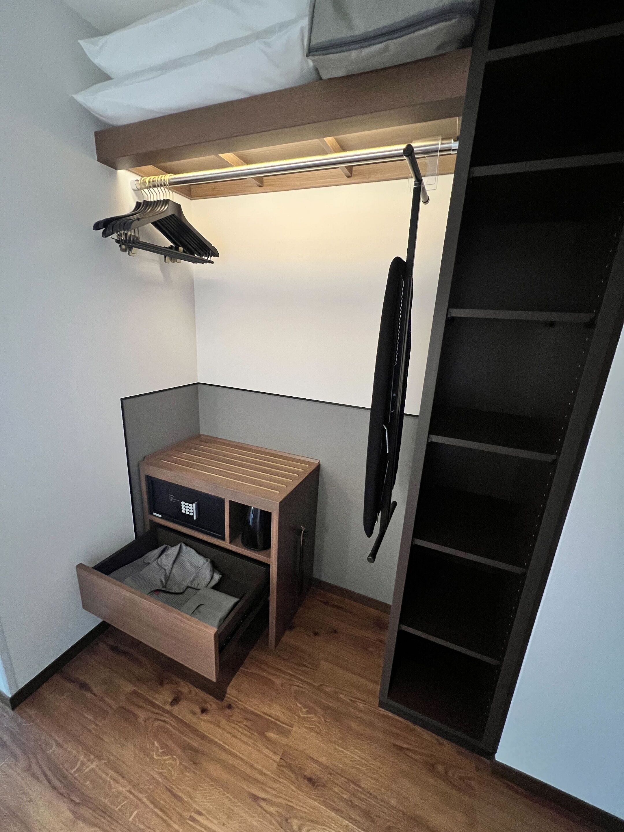 Ein kleines Zimmer mit einer integrierten Bettenlösung, einer kleinen Sitzecke und einem Kleiderschrank.