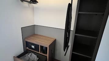 Ein kleines Zimmer mit einer integrierten Bettenlösung, einer kleinen Sitzecke und einem Kleiderschrank.
