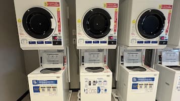 Three stacked laundry machines with control panels and instructions.