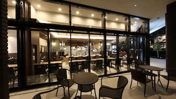 Un restaurant moderne avec des murs en verre, une salle à manger intérieure et une cuisine ouverte.