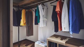 Un portant à vêtements avec différents articles, une valise et un meuble en bois.