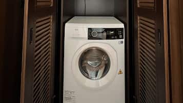 A front-loading washing machine in a laundry room with wooden paneling on the walls.
