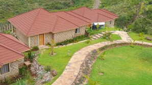 A stone building with a red roof, surrounded by a well-maintained lawn and a stone pathway.