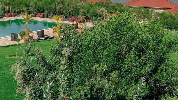A resort with multiple red-roofed buildings, a swimming pool, and lush greenery.