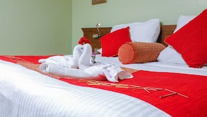 A neatly made bed with white and red bedding, a wooden headboard, and a red throw blanket.