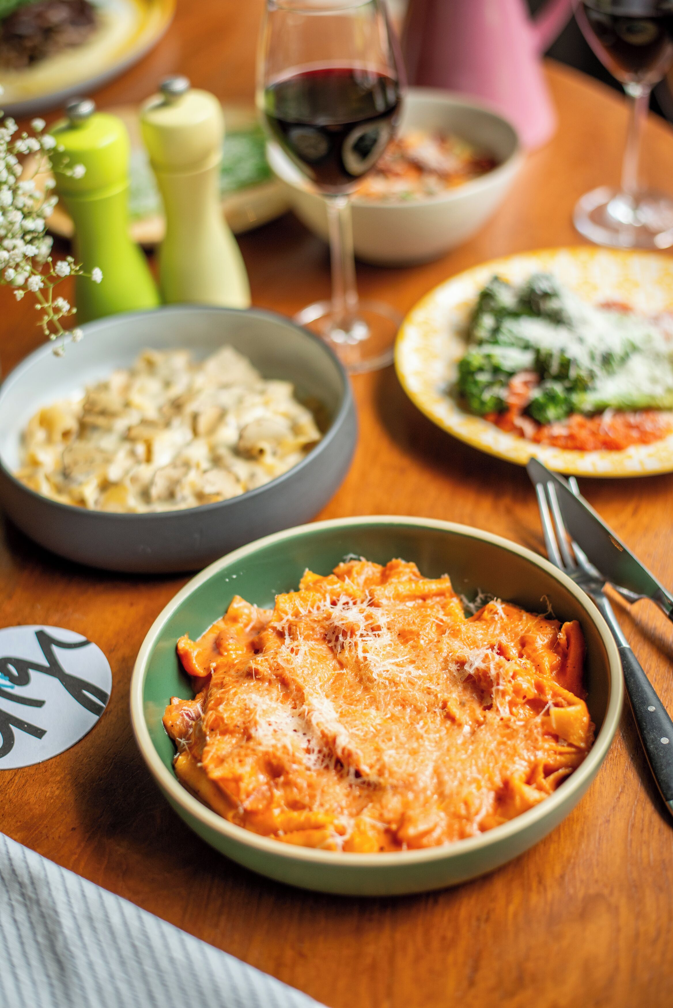 A dining table with various dishes, including pasta and a bowl of soup.