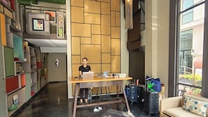 Un hall d’hôtel moderne avec un séparateur en bois, un bureau avec un ordinateur portable et des bagages.