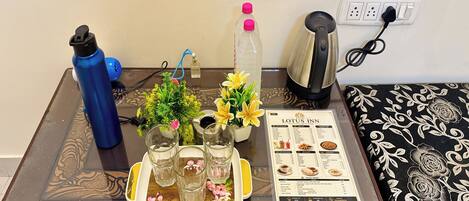 A table with a menu, a water bottle, a kettle, and a small plant.