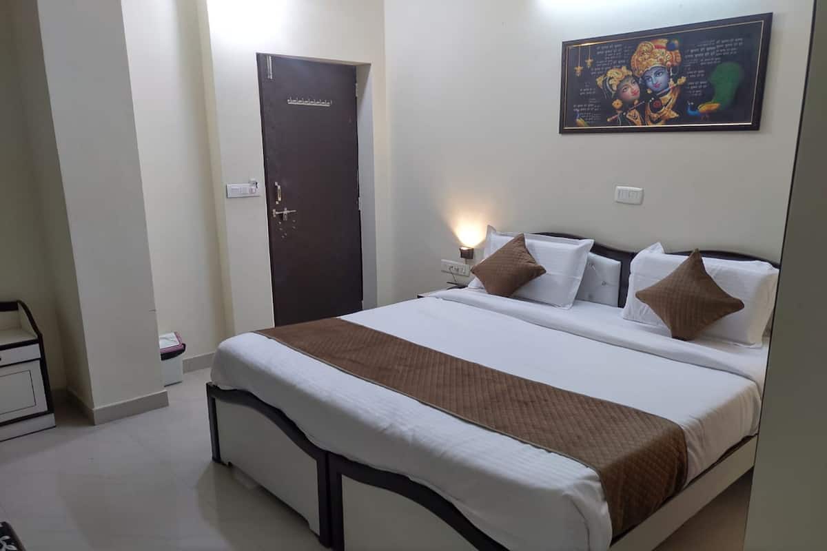 A neatly made bed with a brown blanket, a dark door, and a wall-mounted picture.