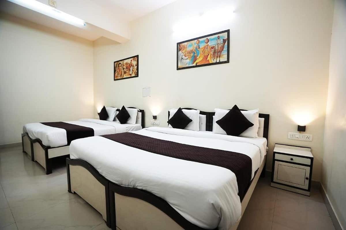 A hotel room with two beds, a nightstand, and artwork on the walls.