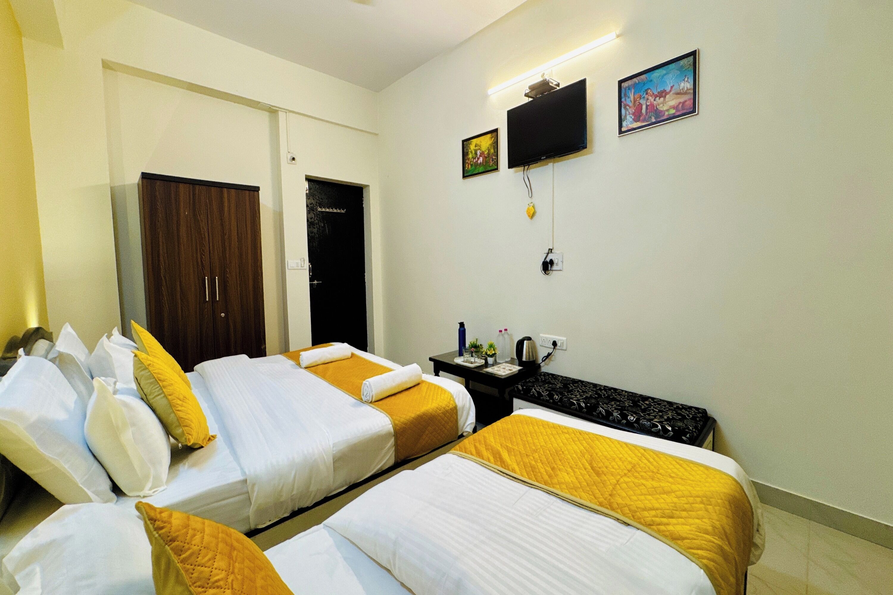 A hotel room with two beds, a desk, a television, and a door.
