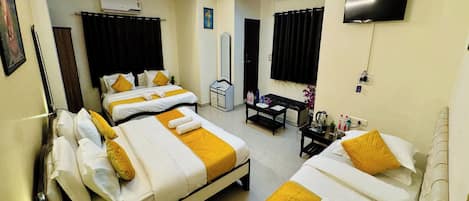 A hotel room with two beds, a desk, a TV, and an air conditioning unit.