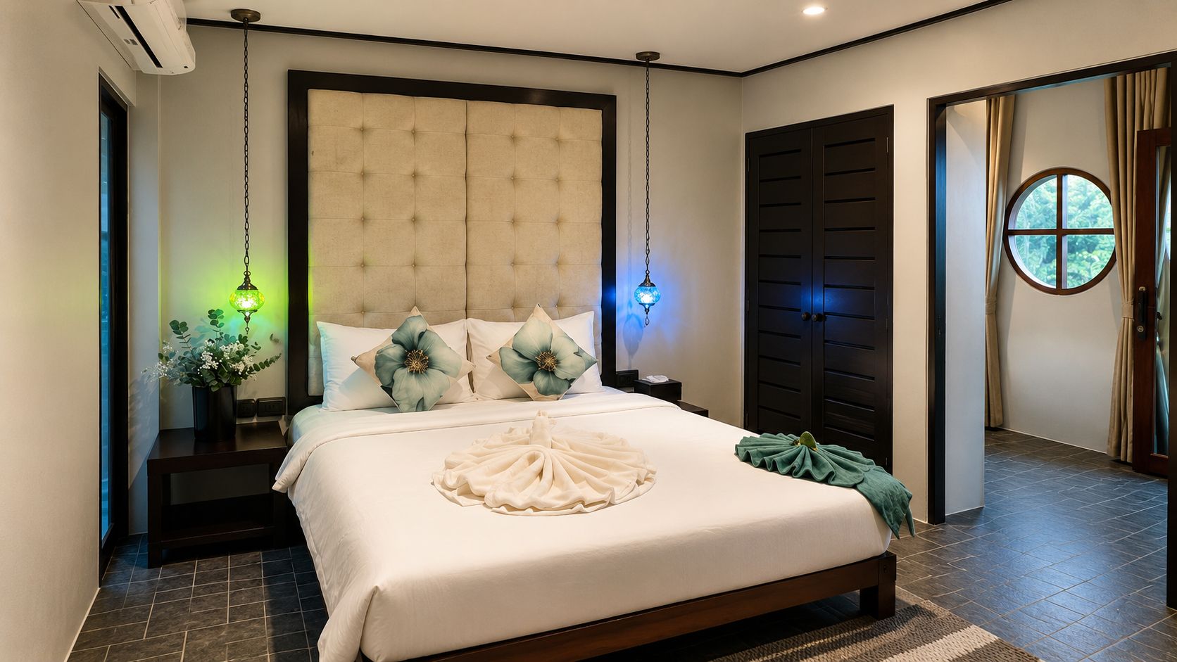 Un dormitorio moderno con una cama grande, un cabecero acolchado, lámparas de noche y vistas al exterior a través de una ventana.