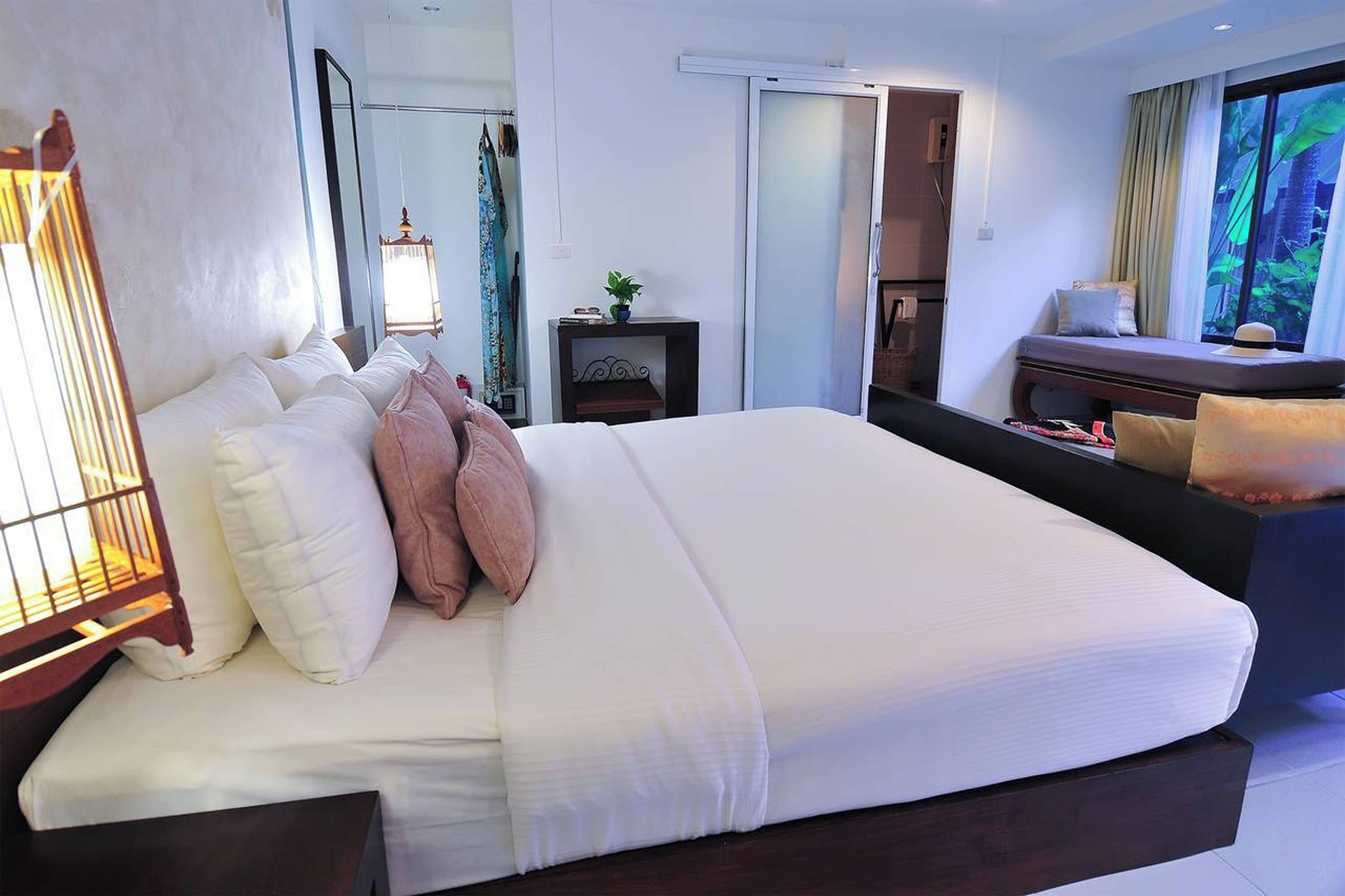 Een moderne hotelkamer met een groot bed, een klein bureau, een spiegel en uitzicht op de omgeving.