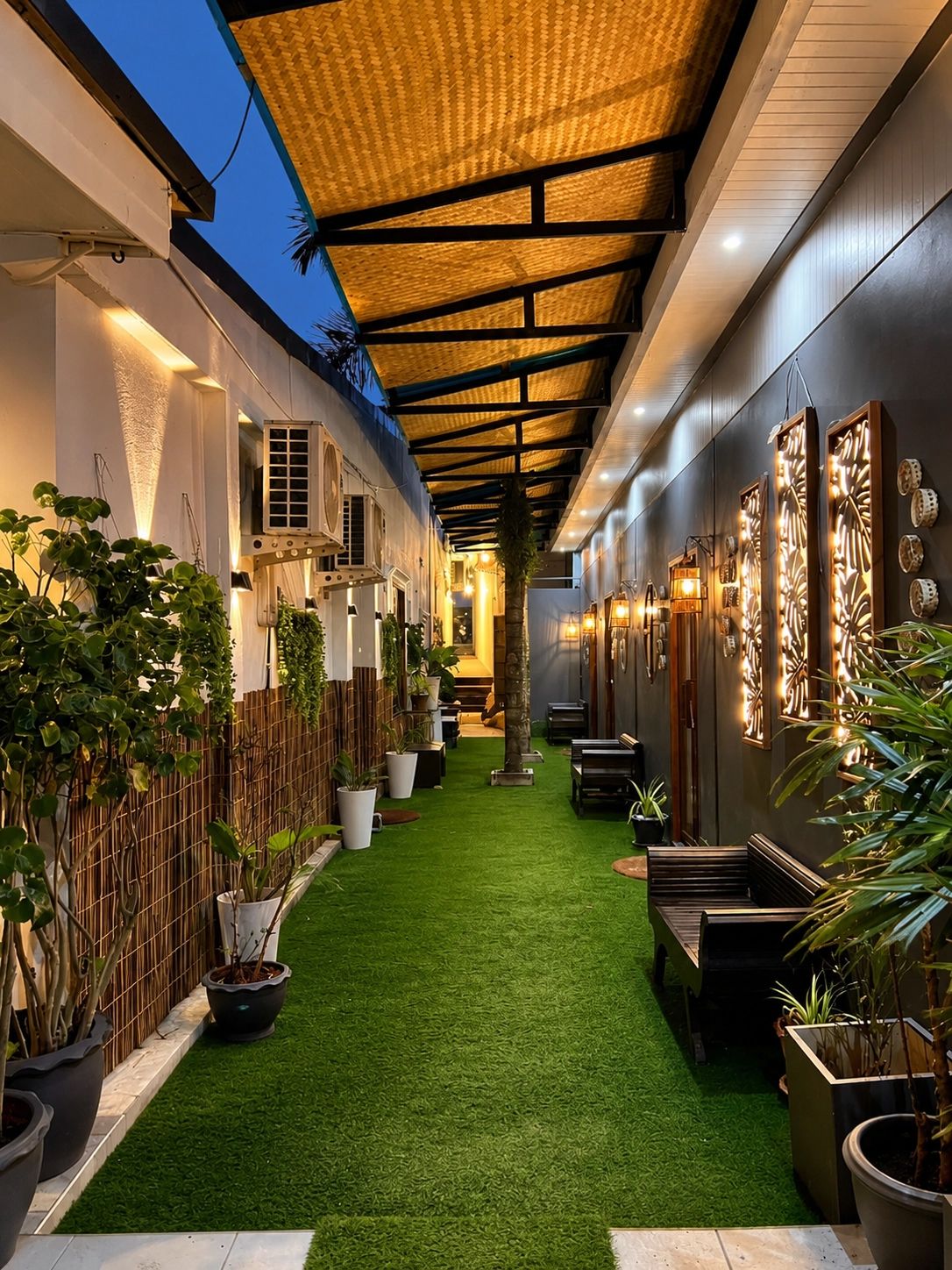 Un espacio exterior cubierto con césped artificial, plantas en macetas y asientos.