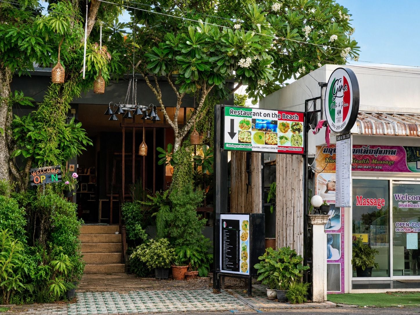 A restaurant with a sign indicating it is open, a menu board, and a massage service sign.