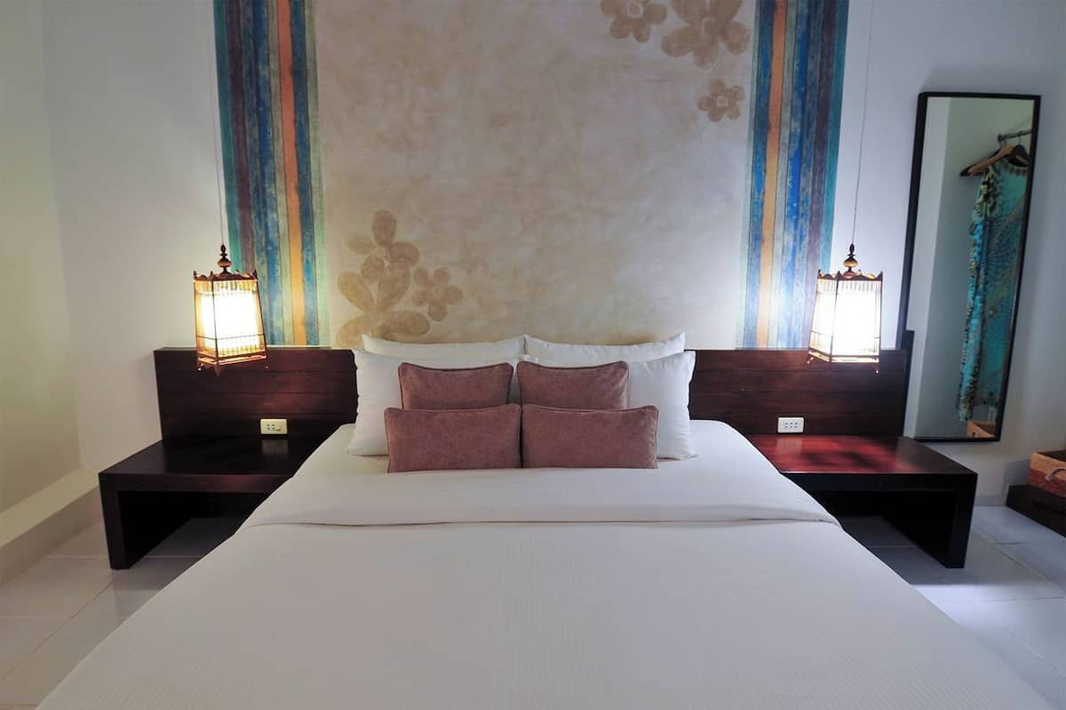 Una camera da letto con un letto grande, due comodini, due lampade a parete e un pannello decorativo.