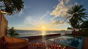 A pool area with a view of the sunset over the ocean, wooden deck, and lounge chairs. - Palm Resort Krabi (Krabi)