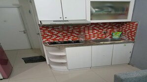 A compact kitchen with white cabinets, a red and white tiled backsplash, a gas stove, and a sink. - S&A Property 5 (Jakarta)