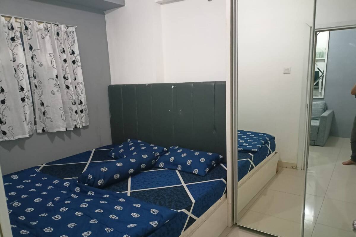 A bedroom with a bed, a headboard, and a window with curtains.
