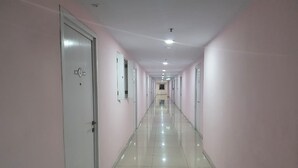 A long, narrow hallway with white tiled floors and pink walls, leading to a door at the end. - S&A Property 5 (Jakarta)