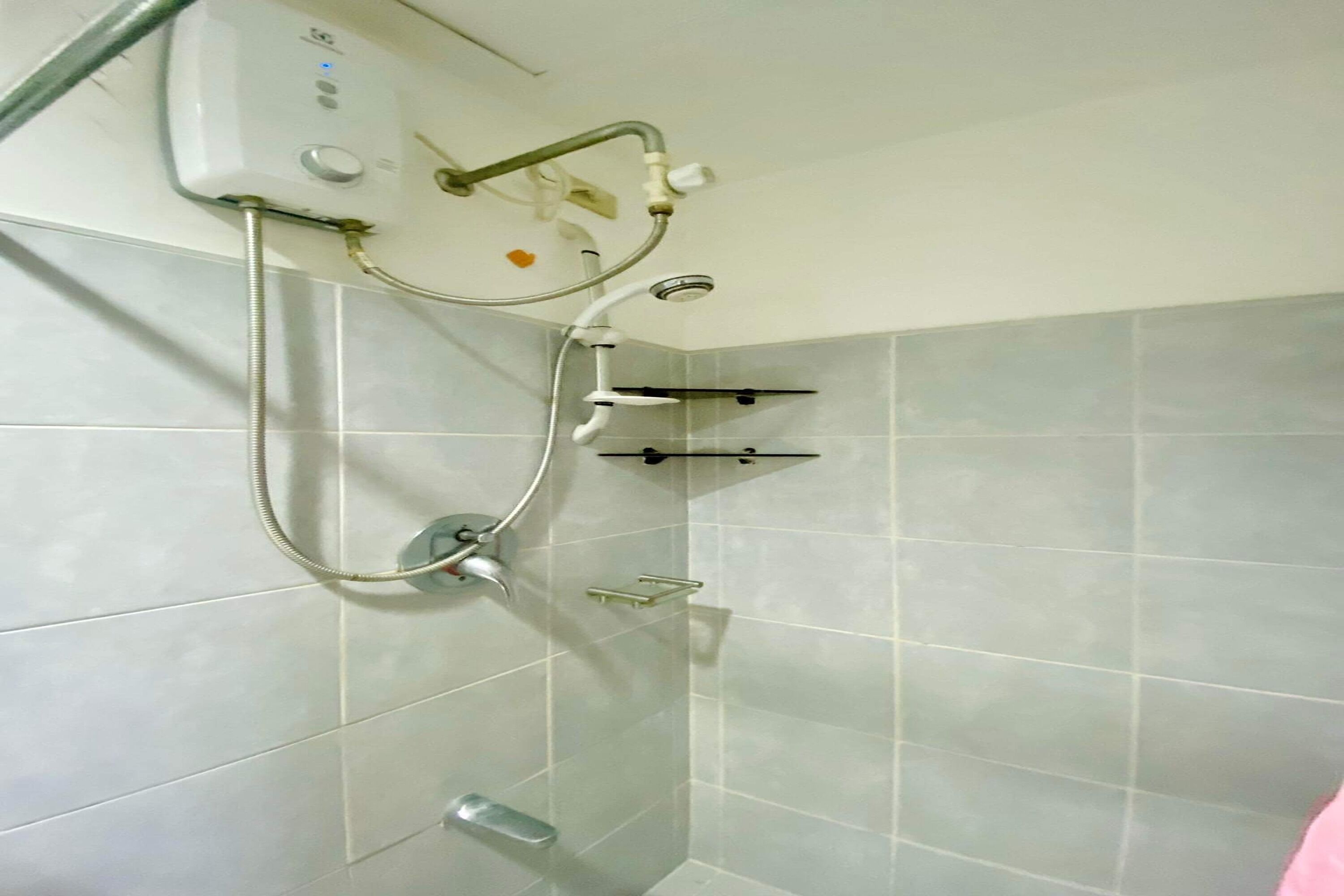A shower with a handheld showerhead, a wall-mounted control panel, and a handheld shower attachment.