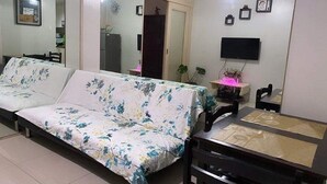 Un salon avec un canapé, un téléviseur et une table à manger.