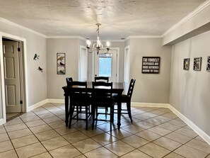 A dining room with a round table and chairs, a chandelier, and artwork on the walls. - Large 4 br Home on an acre in a neighborhood setting -The Cajun Nest- (Opelousas)