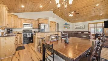 A spacious kitchen with wooden cabinets, stainless steel appliances, and a large dining table with chairs.