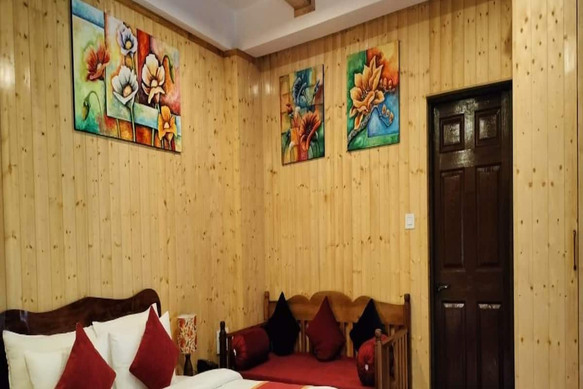 A wooden-paneled room with a bed, a smaller bed, and a door.