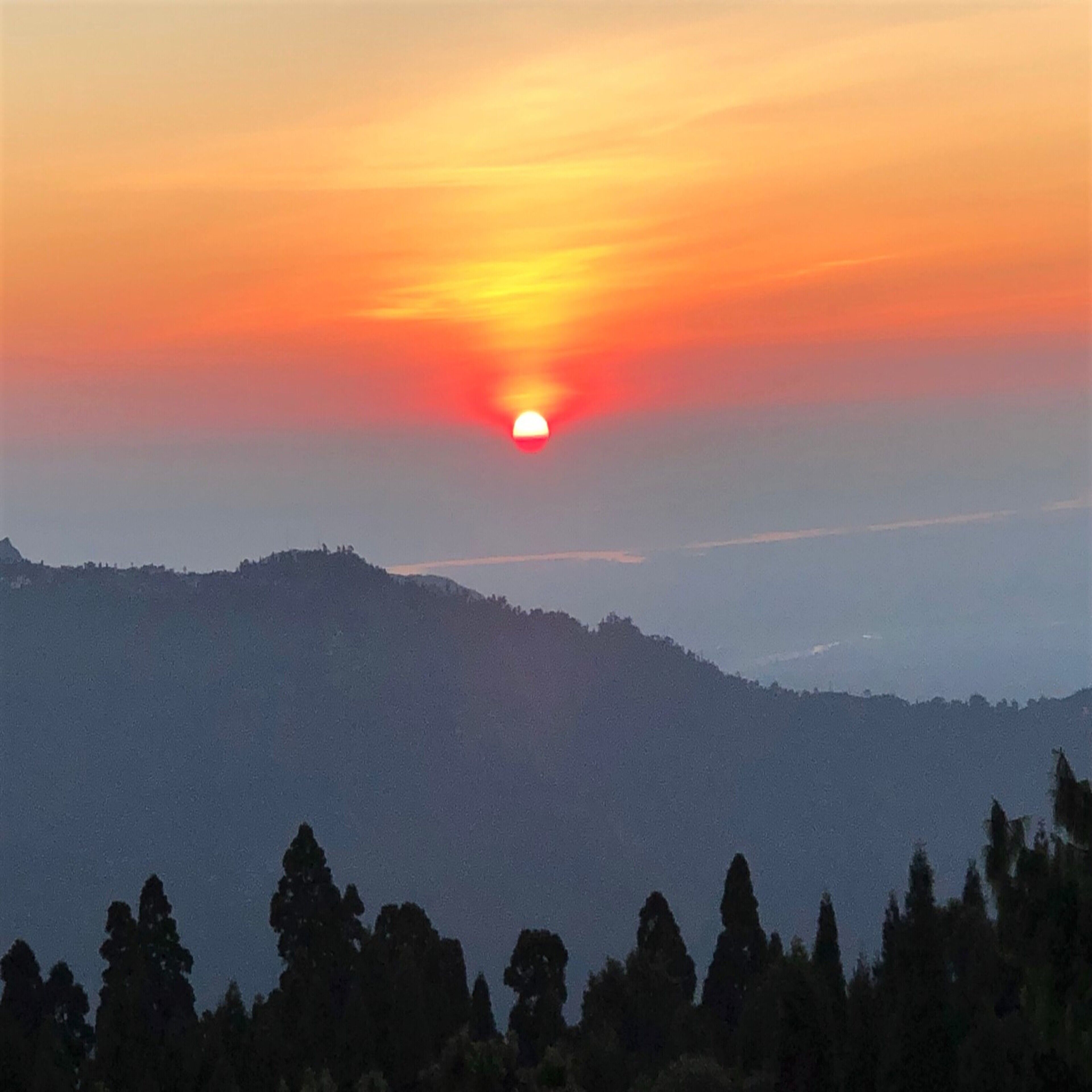 Un atardecer sobre una cordillera con cielo despejado.