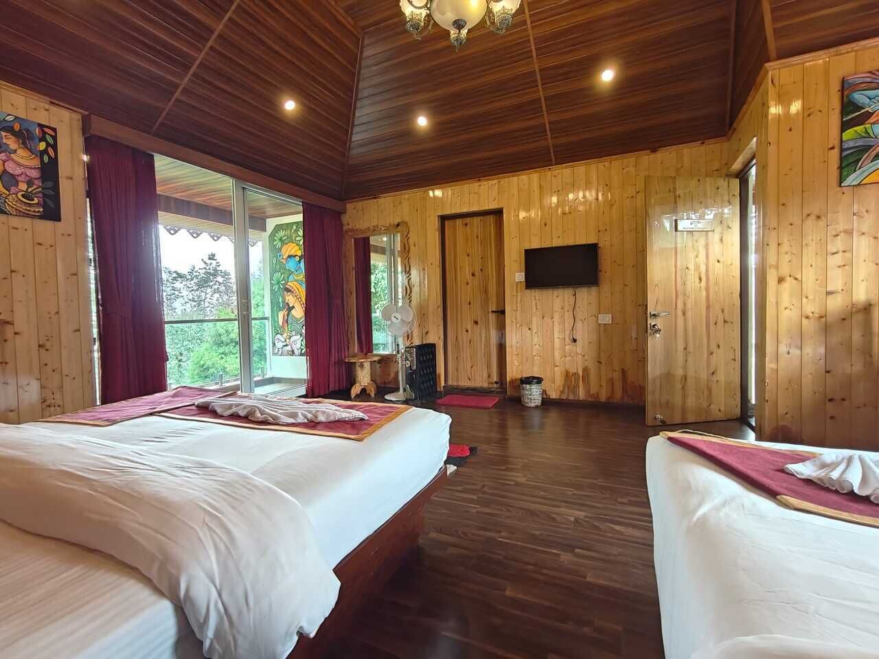 A wooden-paneled room with two beds, a TV, and a large window.